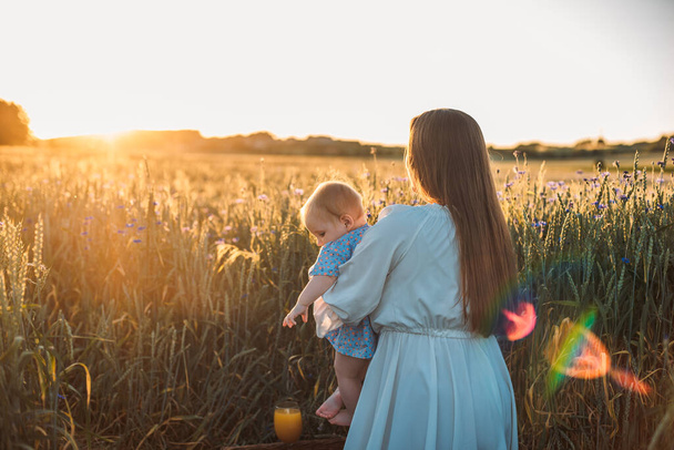 mother and daughter having a picnic outdoors in the field. Playing and having fun with little baby. Happy family concept - Foto, Imagen