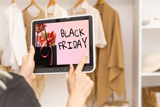 жінка шукає інтернет-магазин, щоб купити подарунки в Інтернеті в чорну п'ятницю з планшетом у вас вдома, руки на сайті з анонсом про угоду на чорну п'ятницю. - Фото, зображення