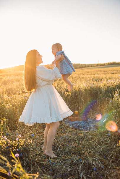 mother and daughter having a picnic outdoors in the field. Playing and having fun with little baby. Happy family concept - Foto, imagen