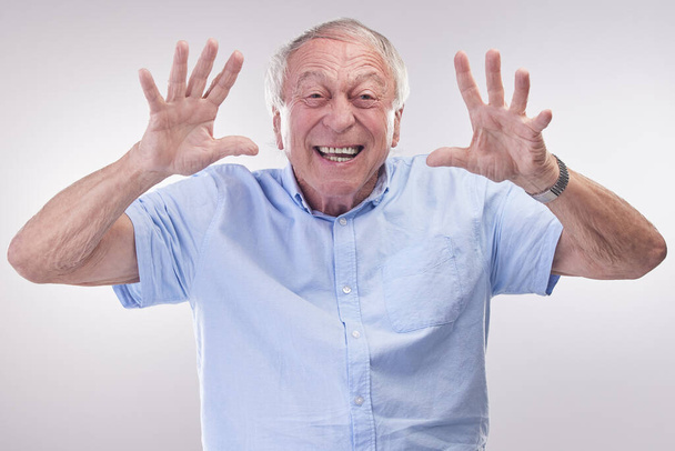 Atrápame si puedes. Captura de estudio de un hombre mayor haciendo un gesto lúdico sobre un fondo gris - Foto, imagen