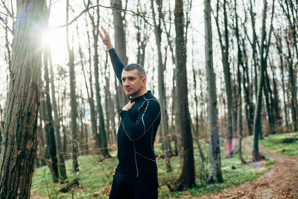 man stretching before running in beautiful spring forest. Sport and wellness concept  - Zdjęcie, obraz