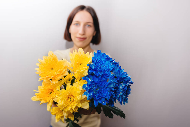 Blue and yellow flowers in hands of girl. Defocused focus on background. Flowers as the State Flag of Ukraine. Copy Space for text. - Photo, Image