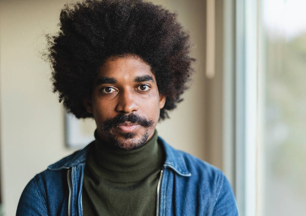 Yüzünde saçı kıvırcık kıvırcık saçlı, kazak ve kot ceket giyen Afro-Amerikan genç adamın yakın portresi. - Fotoğraf, Görsel
