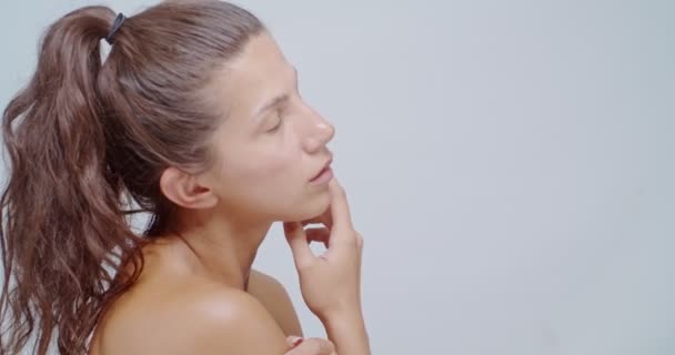 Belleza mujer aplicando cosméticos en su piel, aislado en blanco - Metraje, vídeo