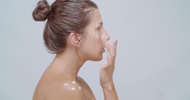 Kráska žena nanášení krém, izolované na bílou - Záběry, video