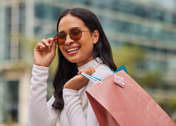 Shopping bag, retail and portrait of woman with sunglasses walking in city after store sale or discount. Happy, smile and rich posh housewife from Mexico shopping for fashion clothes in urban town - Photo, Image