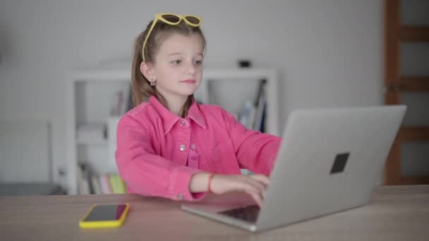 Гордая маленькая девочка печатает на ноутбуке и заканчивает работу - Кадры, видео