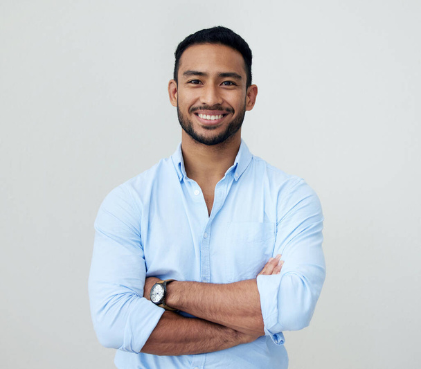 Stay confident as you push through to your goals. Portrait of a confident young businessman standing with his arms crossed against a white background - Foto, imagen