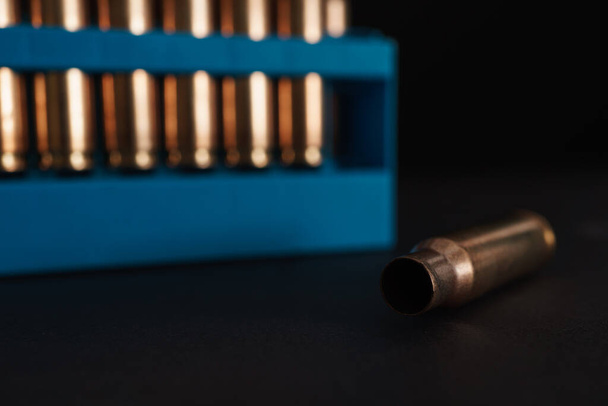 Amber gold empty bullet cases in blue holder aginst a dark black background with copy space available - Photo, Image