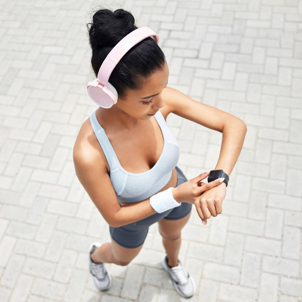 Fitness, kobieta i zegarek biegacza czas monitorowania zdrowia, wydajności i odległości powyżej na zewnątrz. Aktywna kobieca aplikacja do sprawdzania nadgarstka po bieganiu na zewnątrz słuchając muzyki do treningu i ćwiczeń. - Zdjęcie, obraz