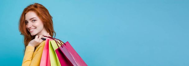 Εμπορική έννοια - εσωτερικη πορτρέτο όμορφη ελκυστική γαλλικό κορίτσι χαμογελά κοιτάζοντας τα φωτογραφικών μηχανών με τσάντα για ψώνια. Μπλε παστέλ φόντο. Χώρο αντίγραφο. - Φωτογραφία, εικόνα
