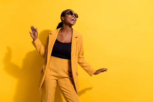 Photo of funky young fancy lady dance look promo wear glasses suit isolated on yellow color background. - Фото, изображение