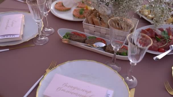 Pratos de aperitivo ficam em uma mesa definida ao lado de placas com placas de nome. Imagens FullHD de alta qualidade - Filmagem, Vídeo