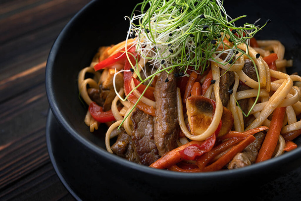 Pasta mit Fleisch, Pilzen und Gemüse auf einem hölzernen Hintergrund mit unscharfem Hintergrund - Foto, Bild