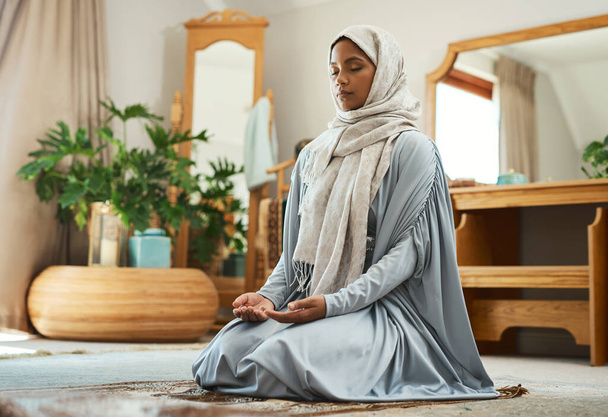期待される心で祈っています。自宅のラウンジで祈っていた若いイスラム教徒の女性が - 写真・画像