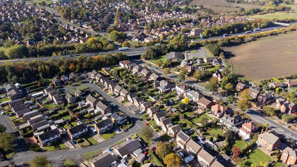 Zdjęcie drona brytyjskiego miasta Wakefield w West Yorkshire, Anglia pokazujące typowe brytyjskie osiedla mieszkaniowe i drogi w pobliżu pola rolniczego i autostrady, nakręcone jesienią. - Zdjęcie, obraz