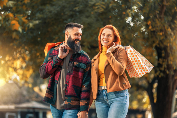Szczęśliwa para z torby na zakupy w jesienny park - Zdjęcie, obraz