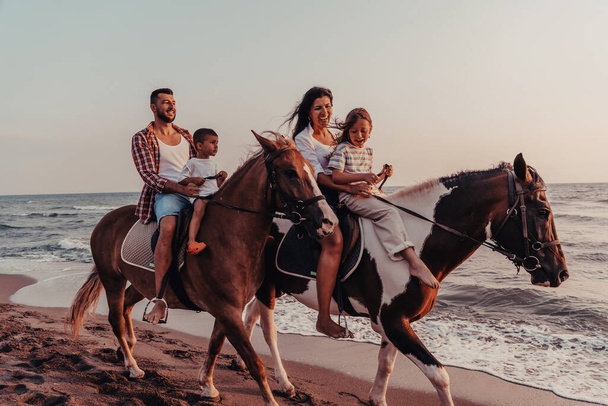The family spends time with their children while riding horses together on a sandy beach. Selective focus. High quality photo - Φωτογραφία, εικόνα