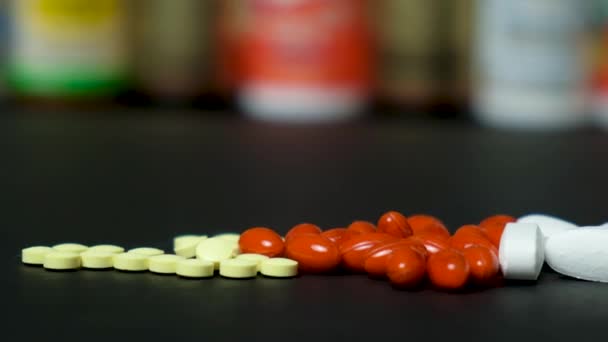 Лекарства или пищевые добавки на черном фоне и банки с таблетками - Кадры, видео