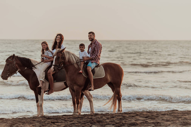 The family spends time with their children while riding horses together on a sandy beach. Selective focus. High quality photo - Fotó, kép