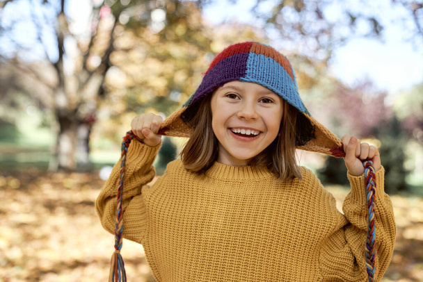 Blank meisje staat in het bos en draagt grappige kleurrijke hoed - Foto, afbeelding