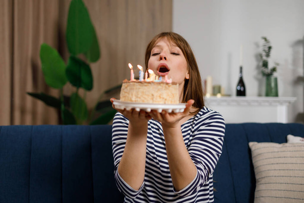 Alles Gute zum Geburtstag. Junge Frau bläst Kerzen auf Geburtstagstorte aus - Foto, Bild