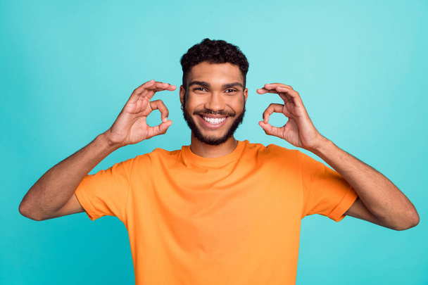 Photo of cheerful man beaming smile orange trendy clothes raise two arm demonstrate okey symbol isolated on cyan color background. - Фото, изображение