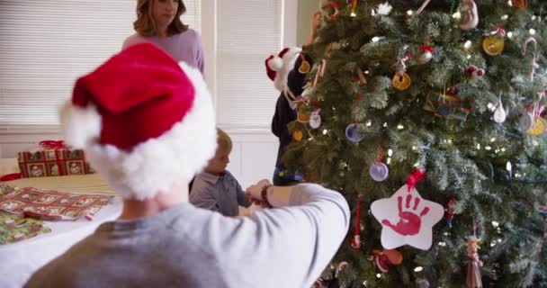 Schöne weiße Familie schmückt gemeinsam den Weihnachtsbaum - Filmmaterial, Video