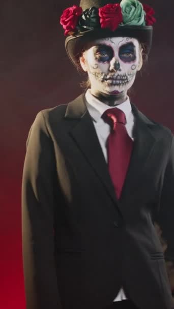 Vertikální video: Děsivá svatá bytost v halloweenském kostýmu s lebkou tvoří oslavu svaté mexické tradice, která vypadá jako dáma smrti. Santa Muerte rituální oslava s černobílým tělem umění - Záběry, video