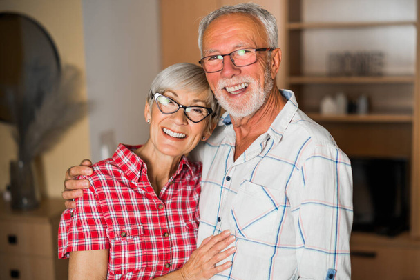 Πορτρέτο ευτυχισμένου ηλικιωμένου ζευγαριού στο σπίτι. Ηλικιωμένοι αγκαλιασμένοι. - Φωτογραφία, εικόνα