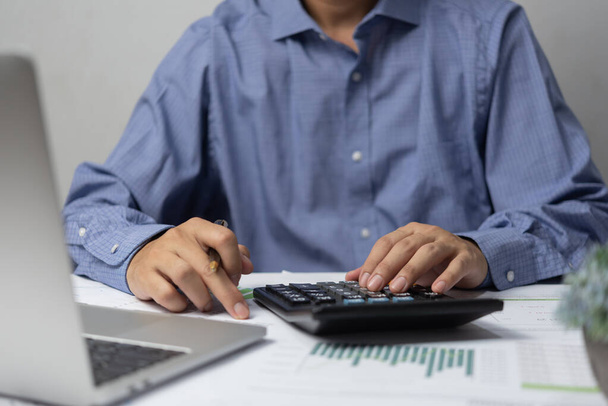 Hombre de negocios mano usando calculadora celebración de pluma y con hacer finanzas y contabilidad fiscal en el escritorio en la oficina en casa. - Foto, Imagen