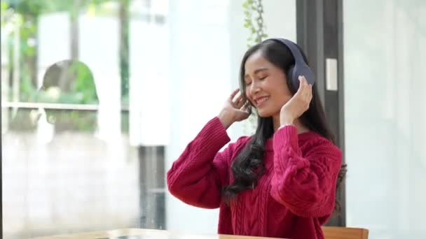 Aantrekkelijke glimlachende jonge vrouw met behulp van tablet en muziek luisteren op de bank thuis. lifestyle concept. - Video