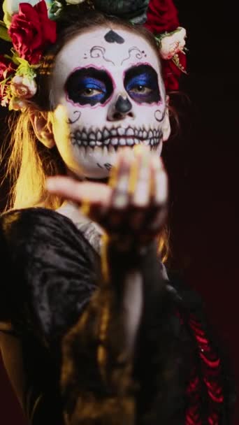 Вертикальное видео: Флиртующая богиня мертвых зовущих и заманивающих жертв, выглядящая как Кавалера Катрина с черно-белым черепом. Святой костюм Санты Муэрте на праздновании мексиканского праздника ужасов - Кадры, видео