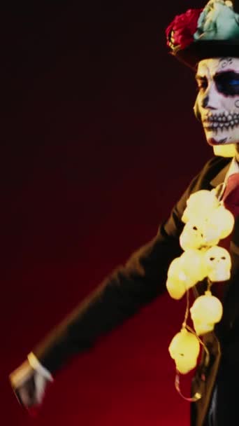 Vídeo vertical: Modelo de terror con disfraz de baile de la muerte en el estudio, escuchando música en auriculares y haciendo movimientos de baile. Pareciendo una santa diosa mexicana para celebrar dios de los muertos - Imágenes, Vídeo