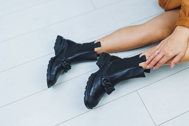 Close up of female legs in black leather boots. Women's autumn shoes. - Фото, изображение