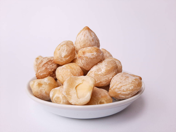 Aleurites moluccanus or Indonesian Candlenuts called Kemiri, inside a smale plate, isolated in white background - Photo, Image