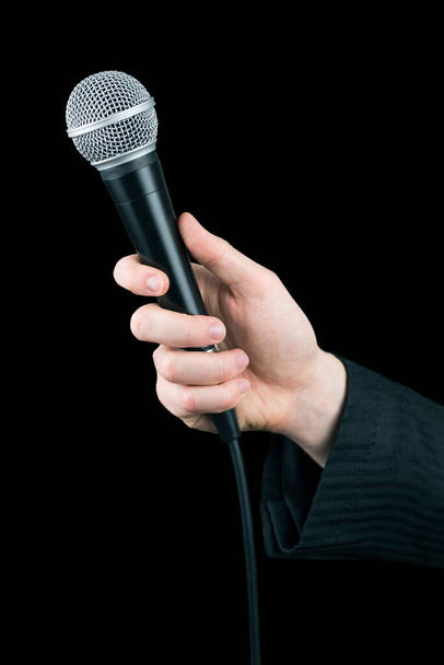 Primer plano del micrófono de mano del hombre aislado sobre fondo negro - Foto, Imagen