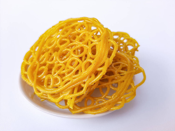Kerupuk Mie Kuning lub Yellow Noodles Krakersy z Indonezji, przed smażone. Wykonane z mąki tapioki i kurkumy. Izolacja na białym tle - Zdjęcie, obraz