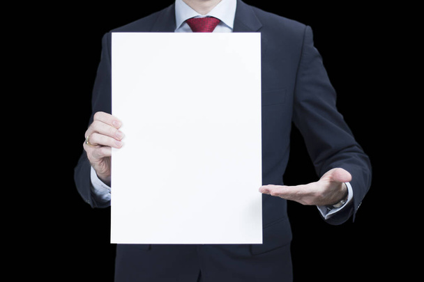 Photo of businessman wearing suit presenting blank poster on black background - Foto, afbeelding