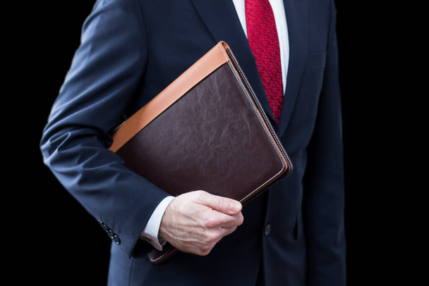 Close up of businessman wearing suit holding documents on black background - Photo, Image