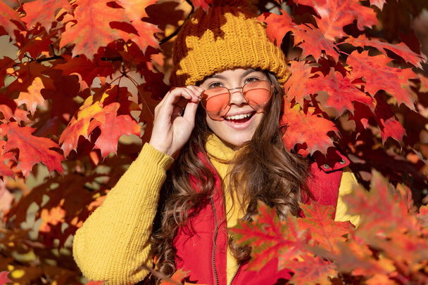 happy teen girl in sunglasses at autumn leaves on natural background. - Photo, Image