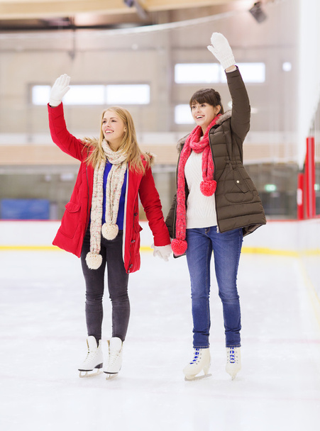 happy girls friends waving hands on skating rink - Fotoğraf, Görsel