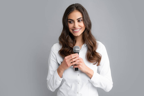 Beautiful business woman is speaking on conference. Portrait of young woman journalist in casual shirt holding microphone, asking questions, discussing problems, interviewing - Photo, Image