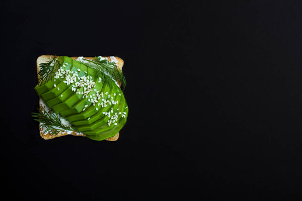 Top view of one sandwich with avocado on the black background. Copy space. - Foto, imagen