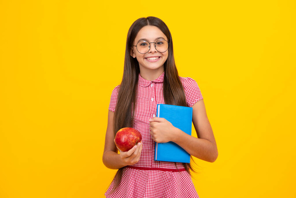 Back to school. Teenager schoolgirl with book ready to learn. School girl children on isolated yellow studio background - Zdjęcie, obraz