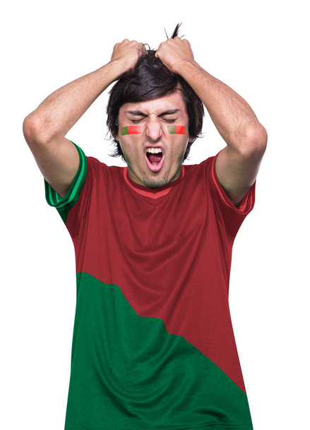 Young sporty soccer fan man with red and green jersey to Portugal, frustrated by the defeat of his favorite team. White background. - 写真・画像