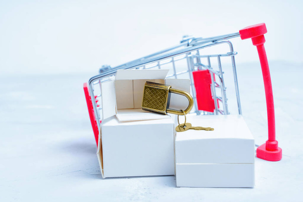 Overturned small shopping trolley with delivery boxes and keyed padlock. E-commerce and privacy concept. - Фото, зображення