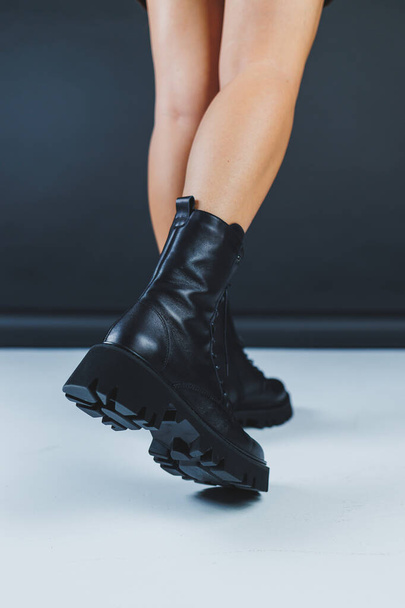 Young woman in black stylish fashion leather lace-up shoes standing on white tile. Fashionable collection of women's autumn shoes. Close-up of female legs in shoes. - Valokuva, kuva