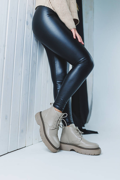Female legs in leather beige autumn boots. A girl stands in a store and measures shoes. - Photo, Image