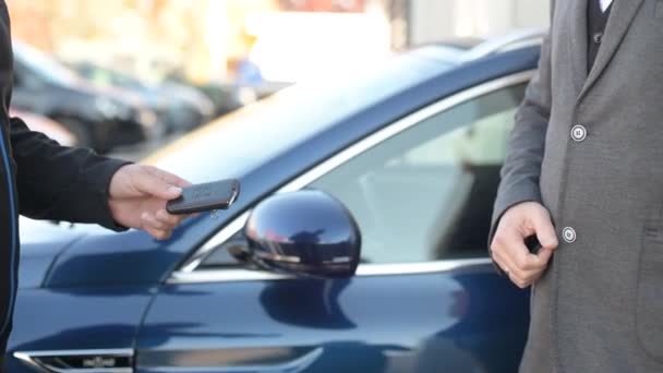 Mechanik, zaměstnanec autoservisu, dává klíče od auta zákazníkovi oblečenému v obleku - Záběry, video